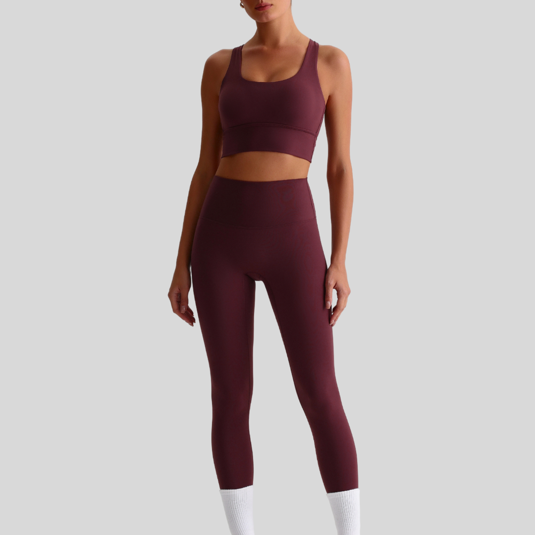 Model wearing KAOS The Label Isla Set in red-brown, showcasing front view of activewear ensemble