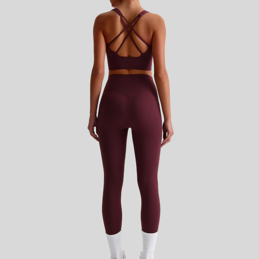 Back view of model in KAOS The Label Isla Set red-brown, highlighting crisscross strap design and high-waisted leggings